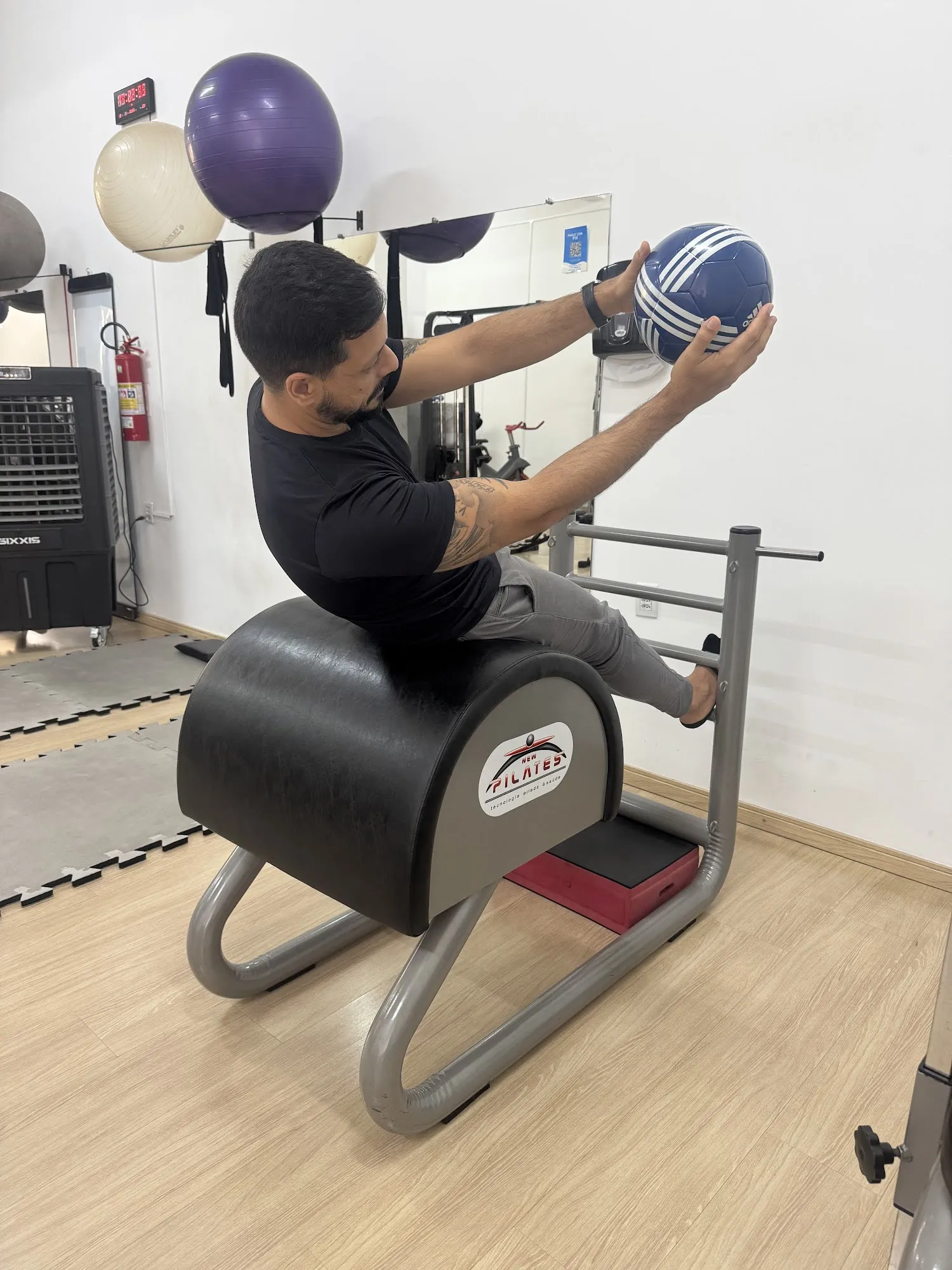 Aluno fazendo exercício com bola no barrel do estúdio de Pilates